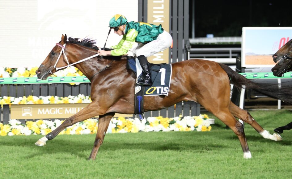 Jockey in green and yellow silks riding a bay horse at full gallop in a horse race, number 1 on the saddle cloth, colorful track backdrop.