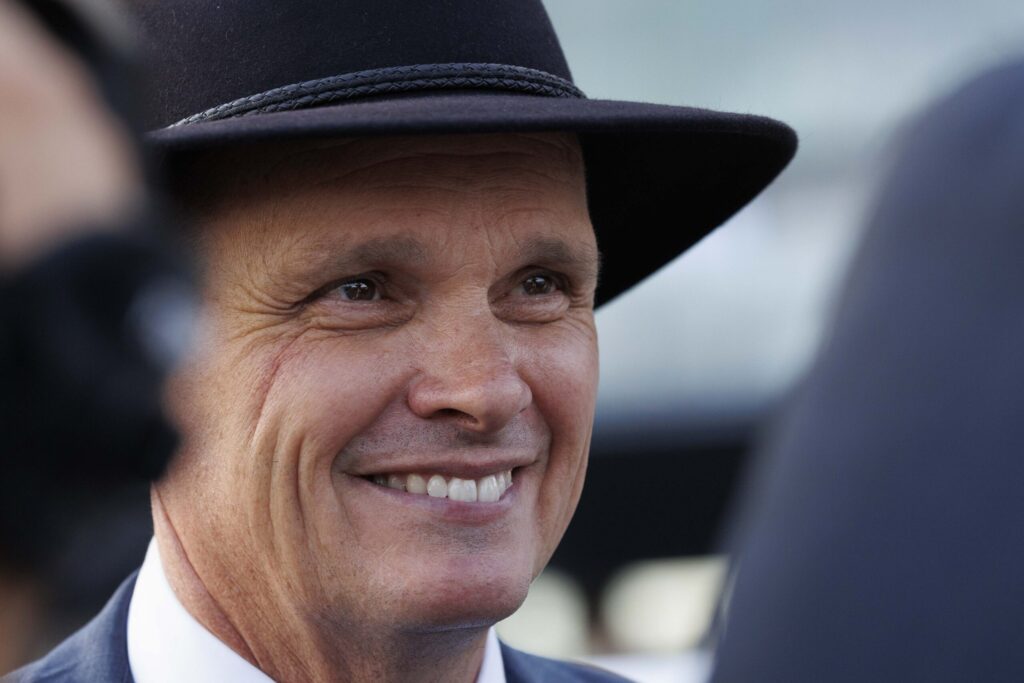 Close-up of a smiling man wearing a black hat, cropped portrait.