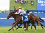 Two jockeys race on competing brown horses near a blue barrier during a horse race, leading with #3 saddle cloth visible.