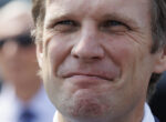 Close-up of a middle-aged man's face with a subtle smile, showing wrinkles around eyes and mouth.