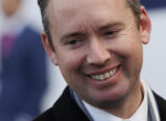 Close-up portrait of a smiling man looking slightly to the left, showing his teeth.