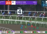 Horses and jockeys race along a turf track under purple banners, with a large '4' sign in the background and a leaderboard at the bottom.
